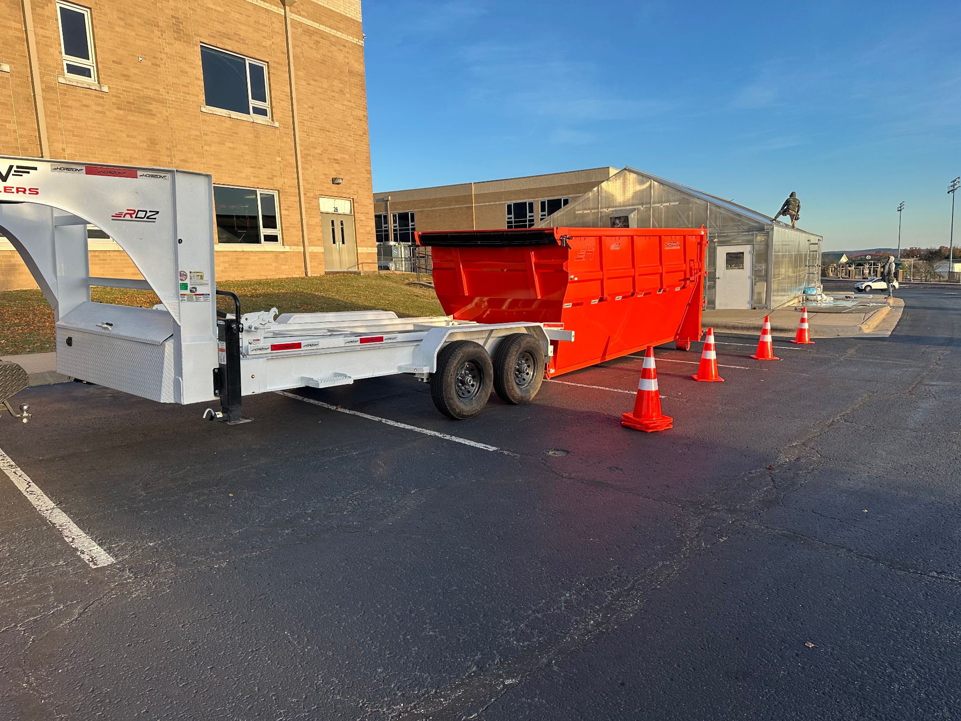 Professional dumpster rental truck delivering red roll-off container for commercial construction site in Branson MO
